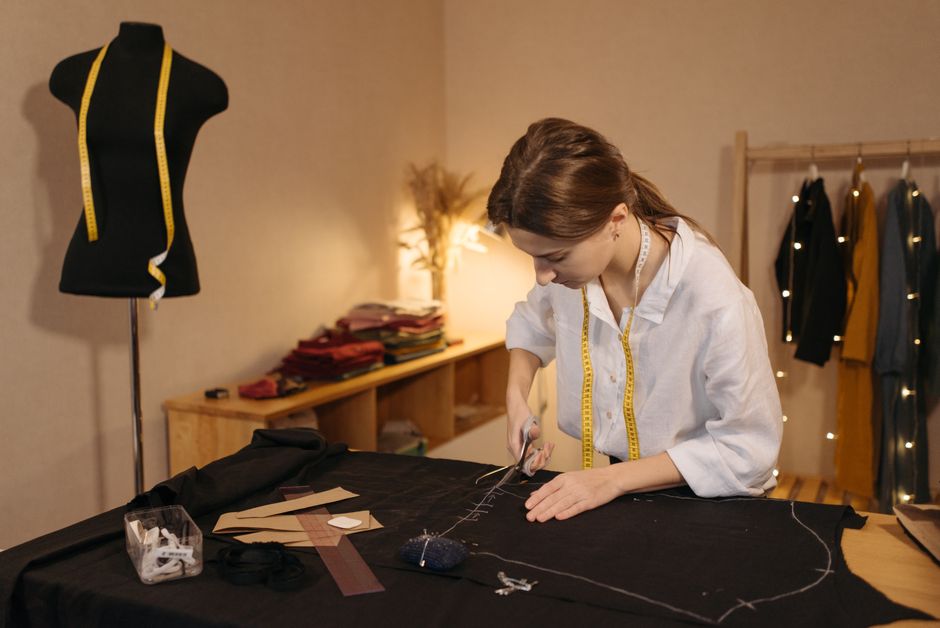 A focused dressmaker cutting fabric in a warmly lit studio, symbolizing creativity and craftsmanship.